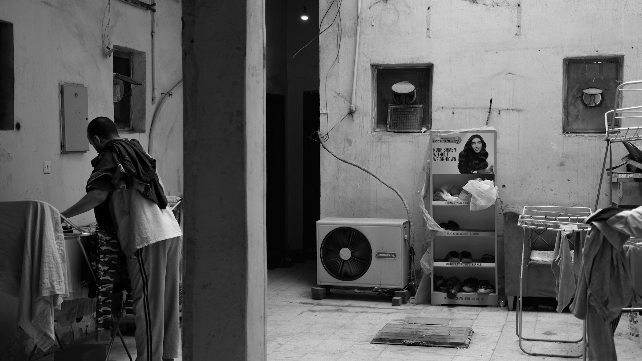 Photograph of a migrant working-class man doing his laundry in a shared accommodation in downtown Kuwait. Photography by Shather Naqi for Noema Magazine.